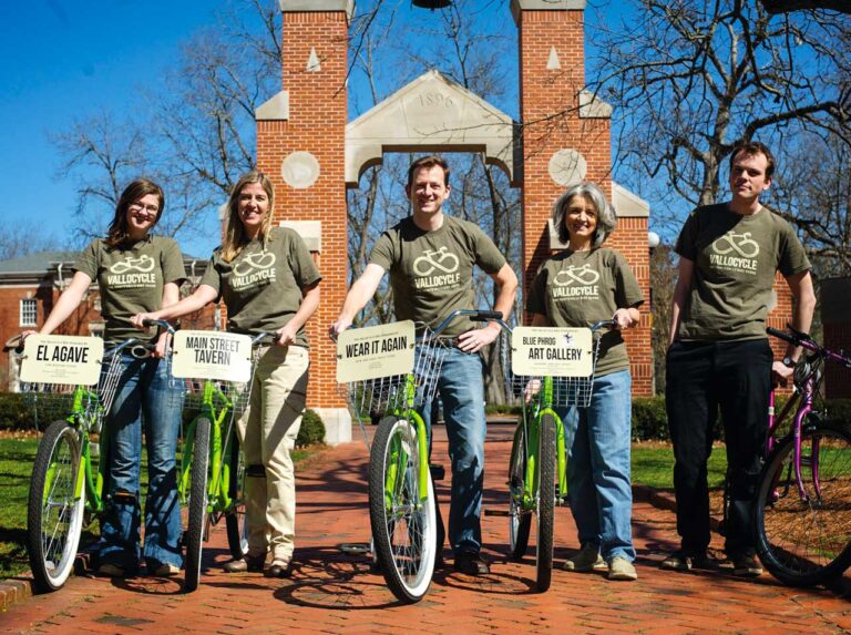 Five people holding bicycles and smiling