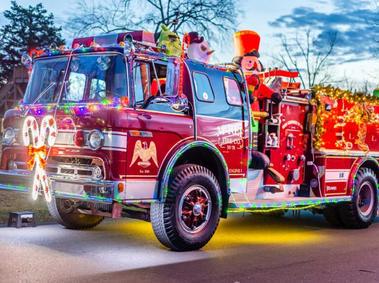A fire truck decorated with lights during a Christmas parade