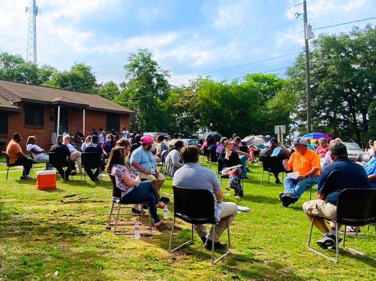 Neighbors sitting on a lawn having a community meeting at Scott Village neighborhood on a sunny day